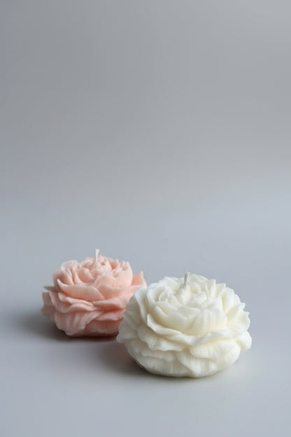 Two soap flowers, one pink and one white, on a white surface.