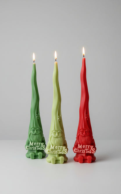 Three Christmas-themed candles with 'Merry Christmas' text on a table with snowflake decorations in the background.